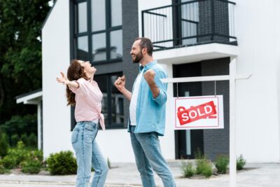 stock-photo-happy-man-woman-celebrating-house-board-sold-letters